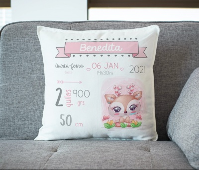 Almofada branca personalizada com dados de nascimento e desenho de cervo cartoon em sofá cinzento.