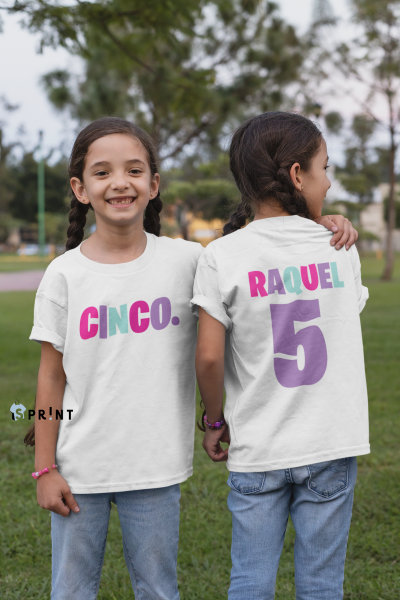 Duas raparigas de t-shirts brancas com textos coloridos e número cinco em parque ao ar livre.
