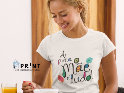 T-shirt branca com texto colorido e flores usada por mulher numa cozinha