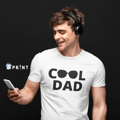 Homem jovem com t-shirt 'COOL DAD', headphones e telemóvel