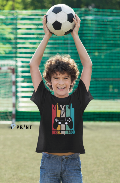 Criança com camiseta preta estampada e bola de futebol no campo