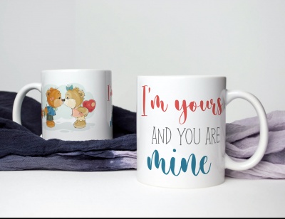 Duas canecas brancas, uma com ursos a beijar e outra com texto em várias cores