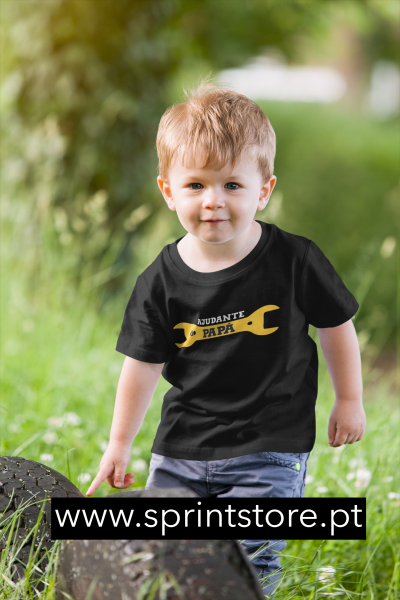 Camisola preta com estampado amarelo 'AJUDANTE DO PAPÁ' usada por criança num ambiente exterior verde