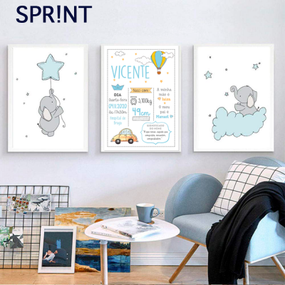 Três quadros infantis com desenho de elefantes e detalhes em azul pendurados numa parede branca acima de uma cadeira azul clara e uma mesa branca