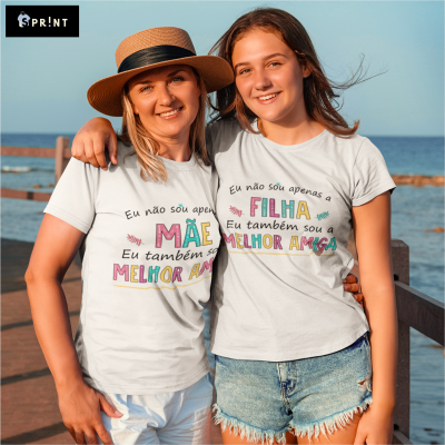 Duas mulheres com t-shirts brancas com texto colorido em português, junto ao mar numa passadeira de madeira
