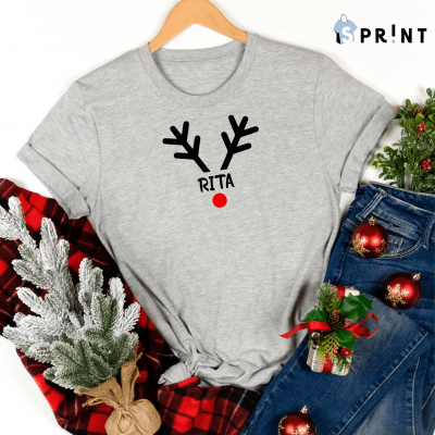 Camiseta cinza com estampado de rena e nome RITA junto a calças de ganga e decoração natalícia