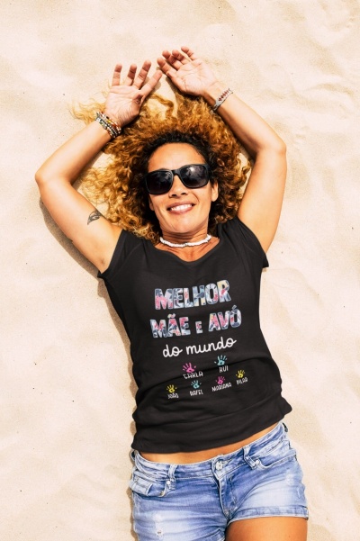 Mulher deitada na areia com t-shirt preta e óculos de sol