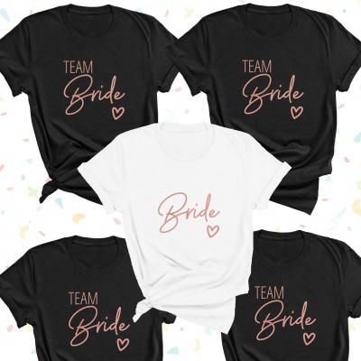 T-shirts pretas com 'TEAM Bride' e t-shirt branca com 'Bride', texto cor de rosa e coração.