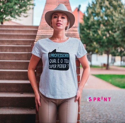 Mulher com t-shirt cinzenta clara com texto sobre ser professora em ambiente exterior