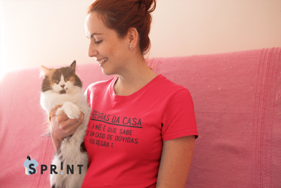 Mulher com camisola rosa segurando gato branco num sofá cor-de-rosa