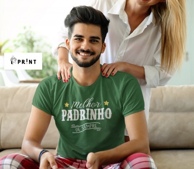Homem sorridente de camiseta verde com texto, sentado no sofá com mulher atrás
