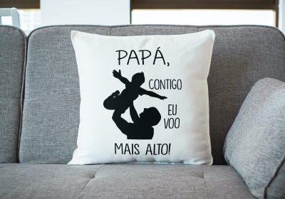 Almofada branca com texto e imagem preta num sofá cinzento.