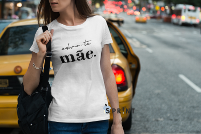T-shirt branca com texto 'adoro-te mãe.' usada numa rua urbana com táxi amarelo ao fundo