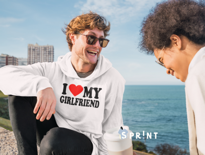 Homem de sweatshirt branca com texto e mulher junto ao mar