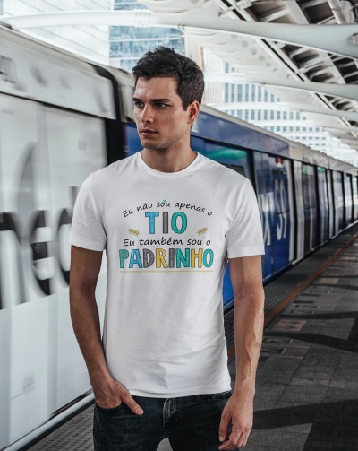 Homem com camisola branca e texto em português na plataforma de estação de metro com comboio ao fundo