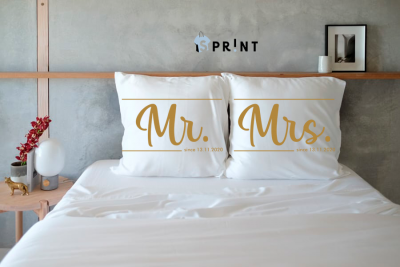 Almofadões brancos com texto Mr. e Mrs. em cama branca e parede cinza com prateleira de madeira