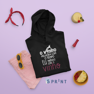 Camisola preta com capuz e texto sobre vinho, calções rosa, óculos, bandana e bebida. 