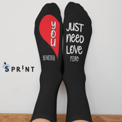 Meias pretas com texto em branco e vermelho com uma mensagem de amor, em fundo de chão de madeira clara.
