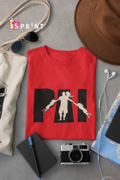 T-shirt vermelha com estampa preta e branca ao centro, rodeada por acessórios de viagem e lazer sobre superfície cinza.