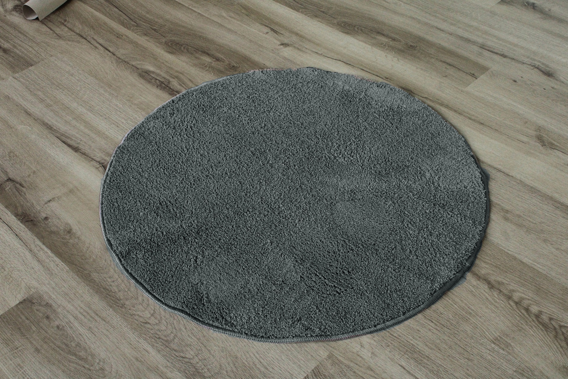 Tapete redondo cinzento sobre chão de madeira clara