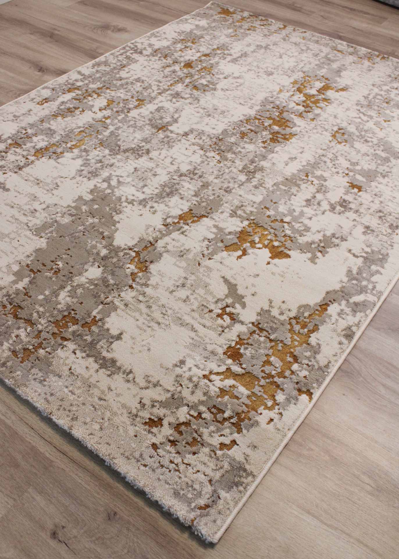Tapete abstrato bege, cinza e dourado em chão de madeira clara
