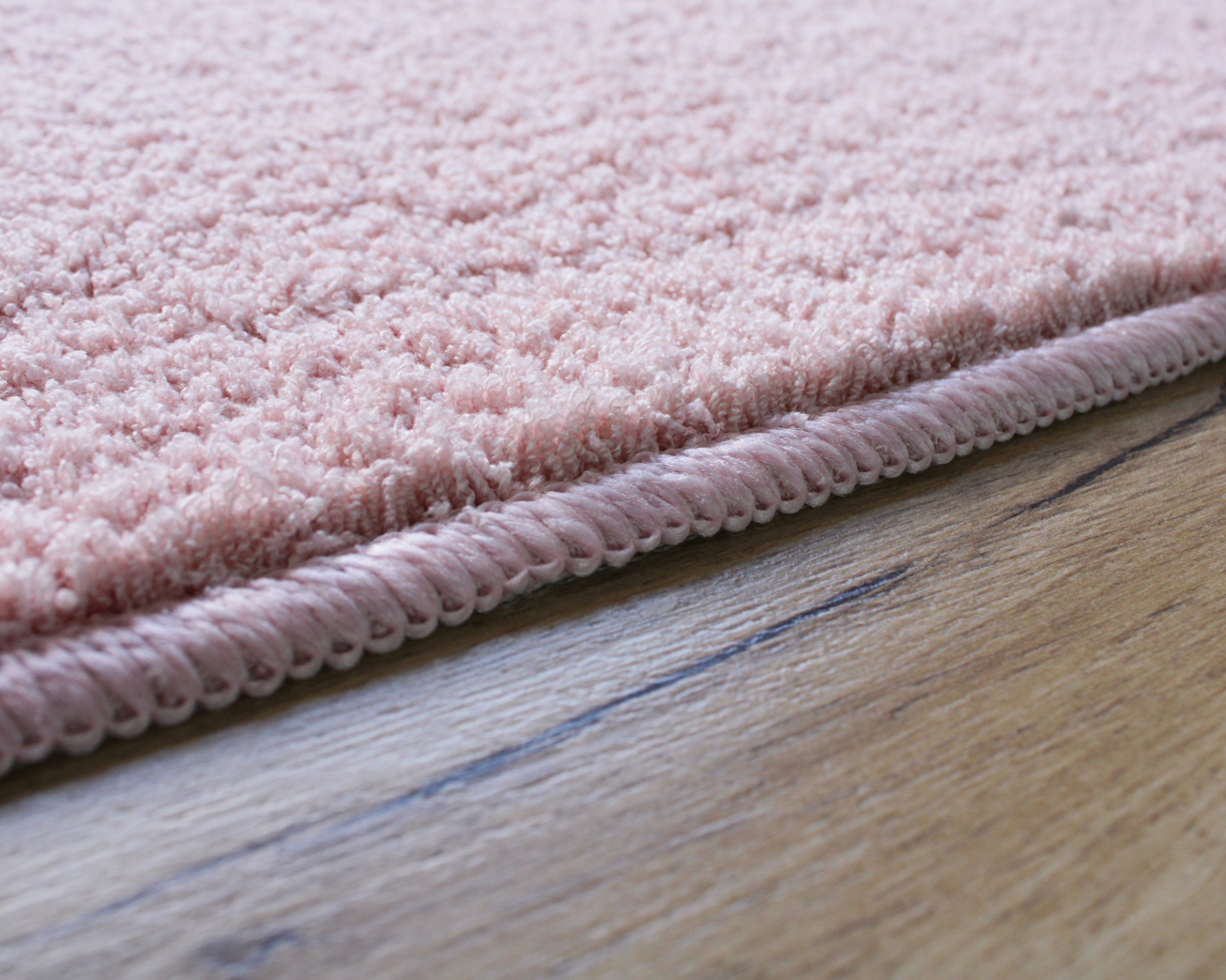 Tapete rosa claro felpudo sobre pavimento de madeira clara
