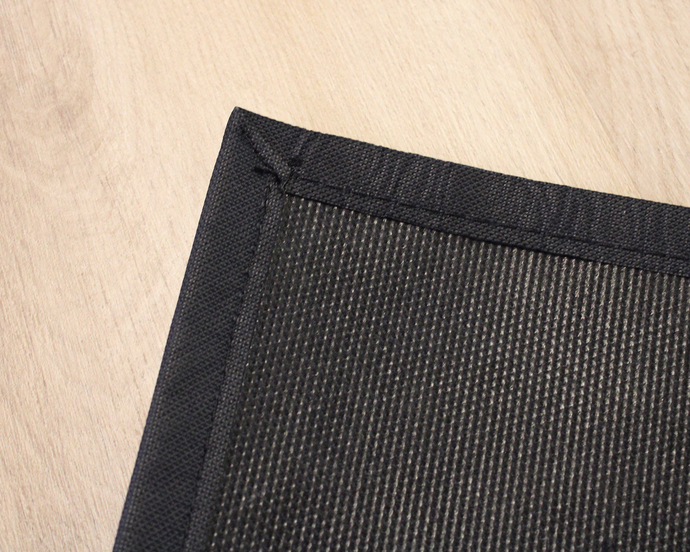 Canto de tapete preto com bordas fotográfico em piso de madeira clara