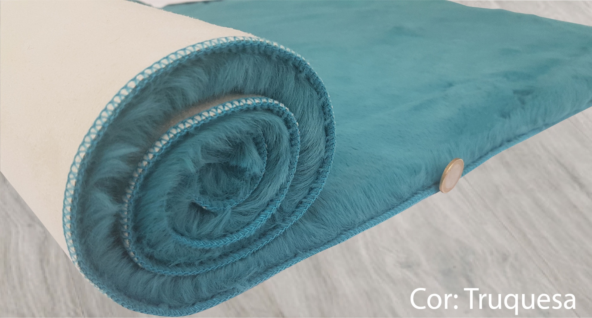 tapete ou manta turquesa com botão de madeira sobre piso claro