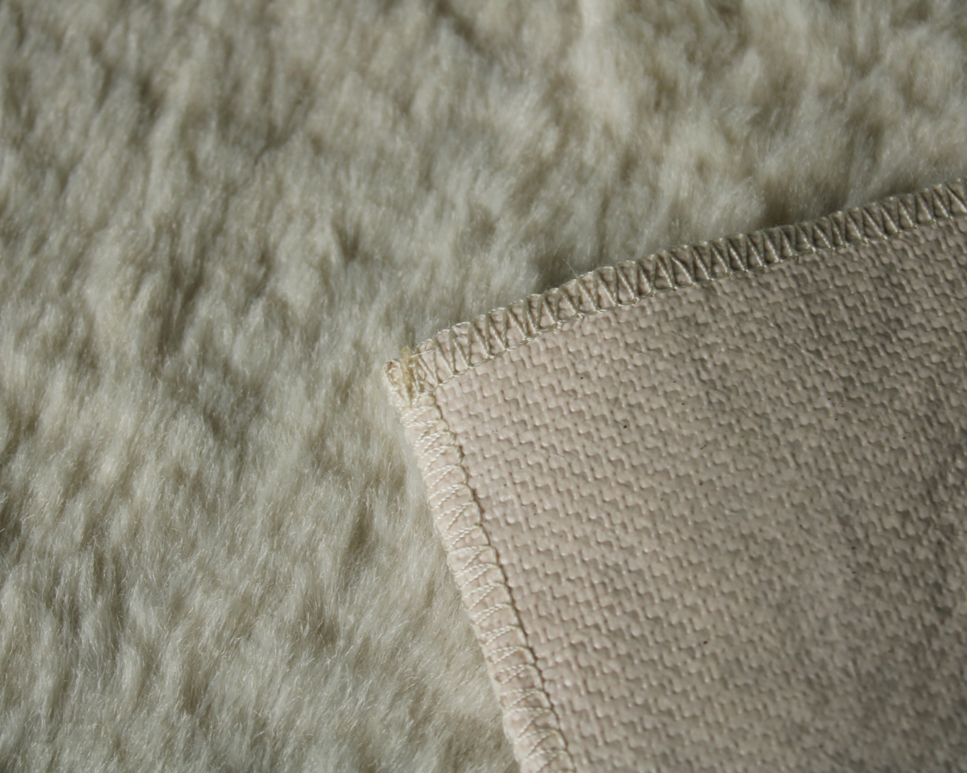 tecido felpudo bege claro com canto de tecido liso e costura em zig-zag