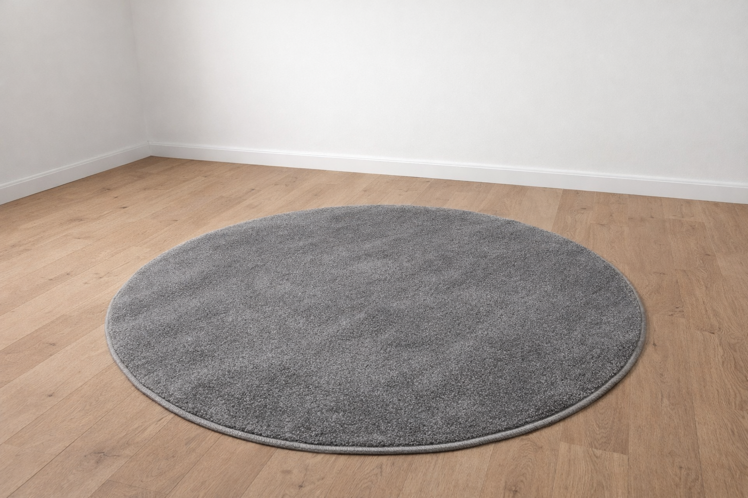 Tapete redondo cinzento sobre chão de madeira clara