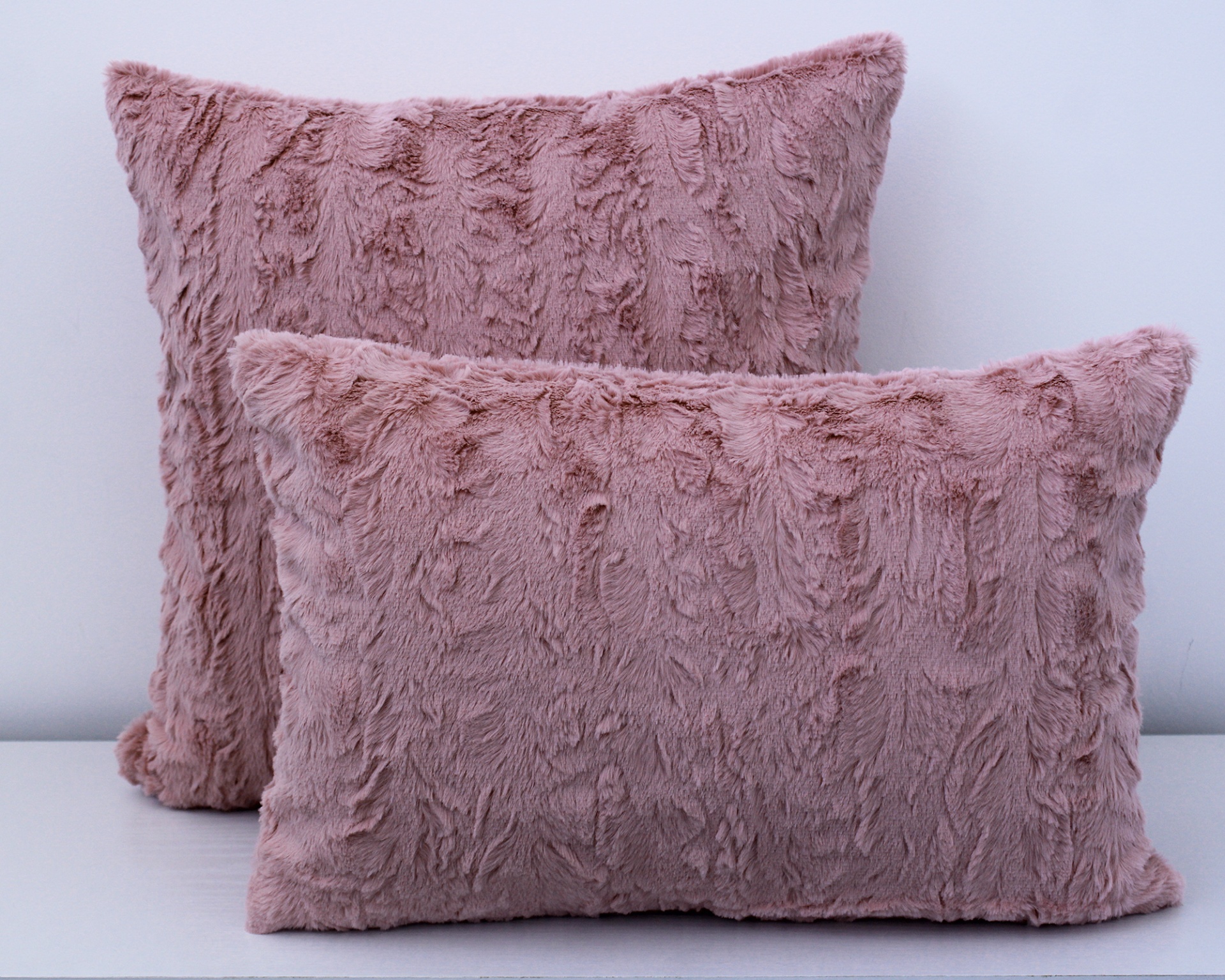 Conjunto de almofadas rosa felpudas em cima de superfície branca