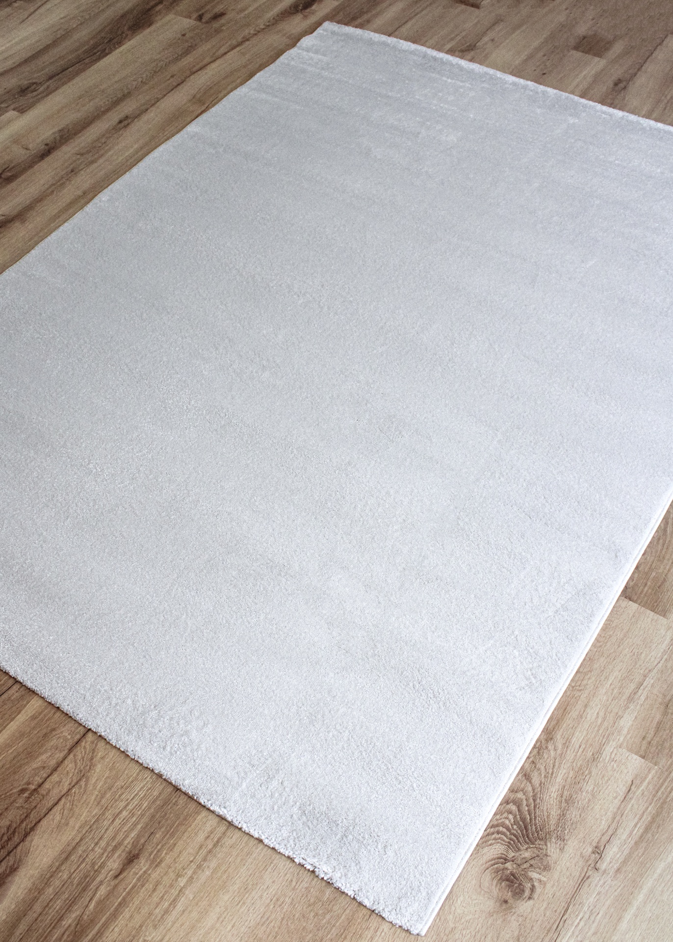 Tapete branco macio sobre chão de madeira clara