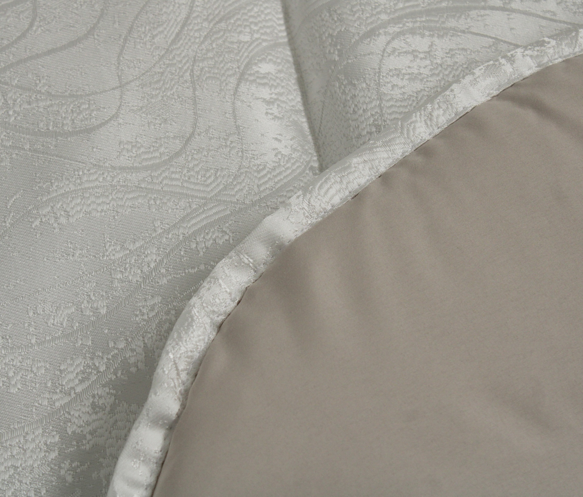 Cobertor ou manta em dois tons de bege, um acetinado com padrão texturizado e outro liso.