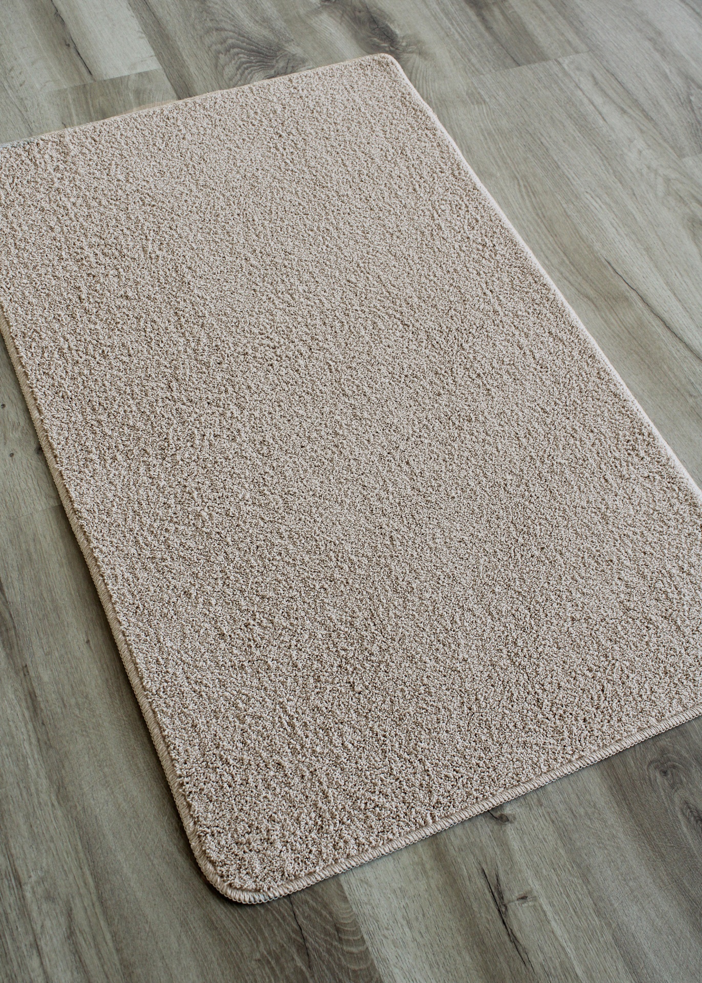 Tapete beige claro com textura macia sobre chão de madeira clara