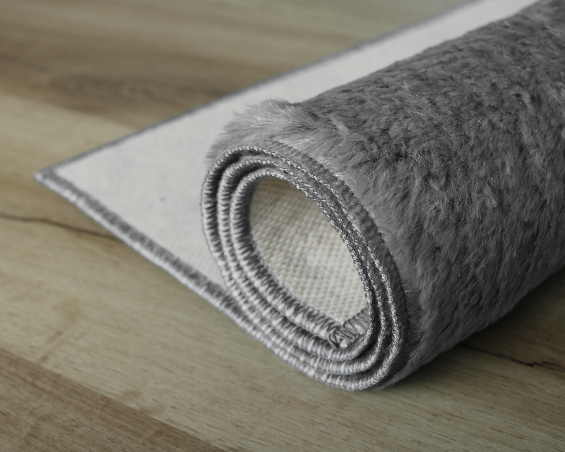 Tapete cinzento felpudo enrolado com base antiderrapante branca