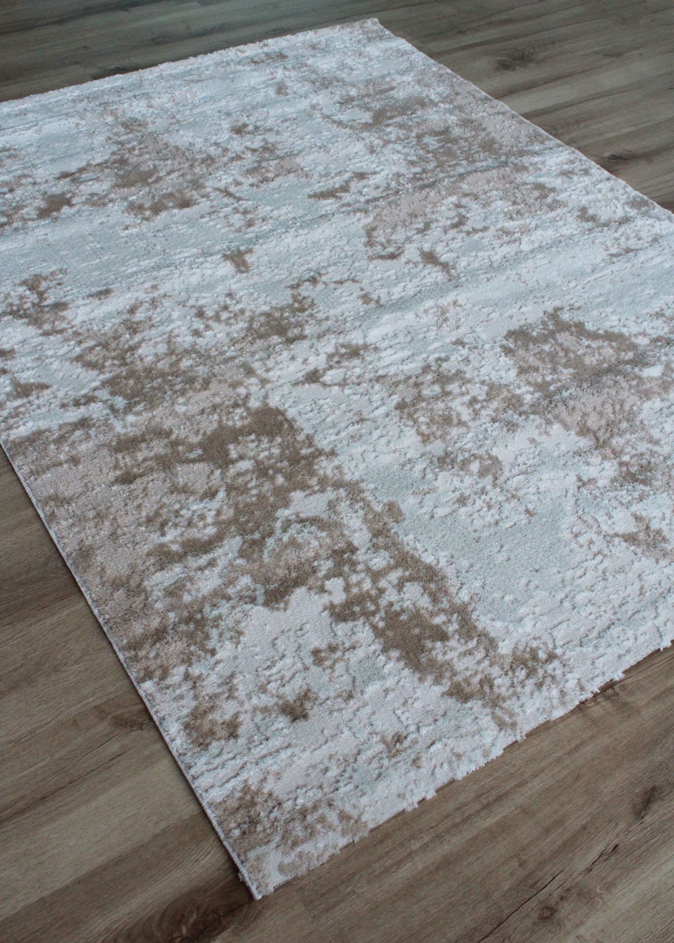 Tapete beige e branco com padrão abstrato sobre chão de madeira