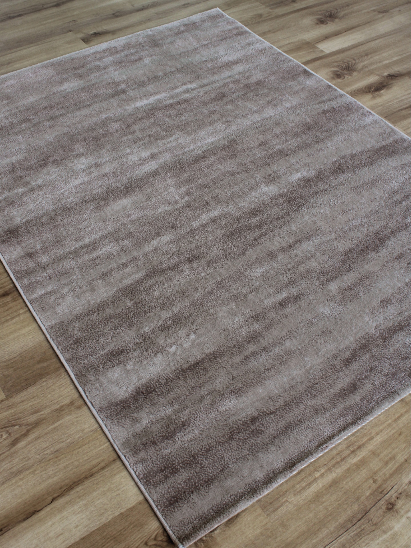 Tapete cinza claro com textura lisa sobre piso de madeira