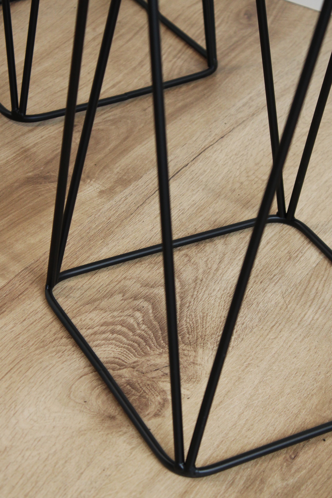 Base metálica preta com design geométrico sobre chão de madeira clara
