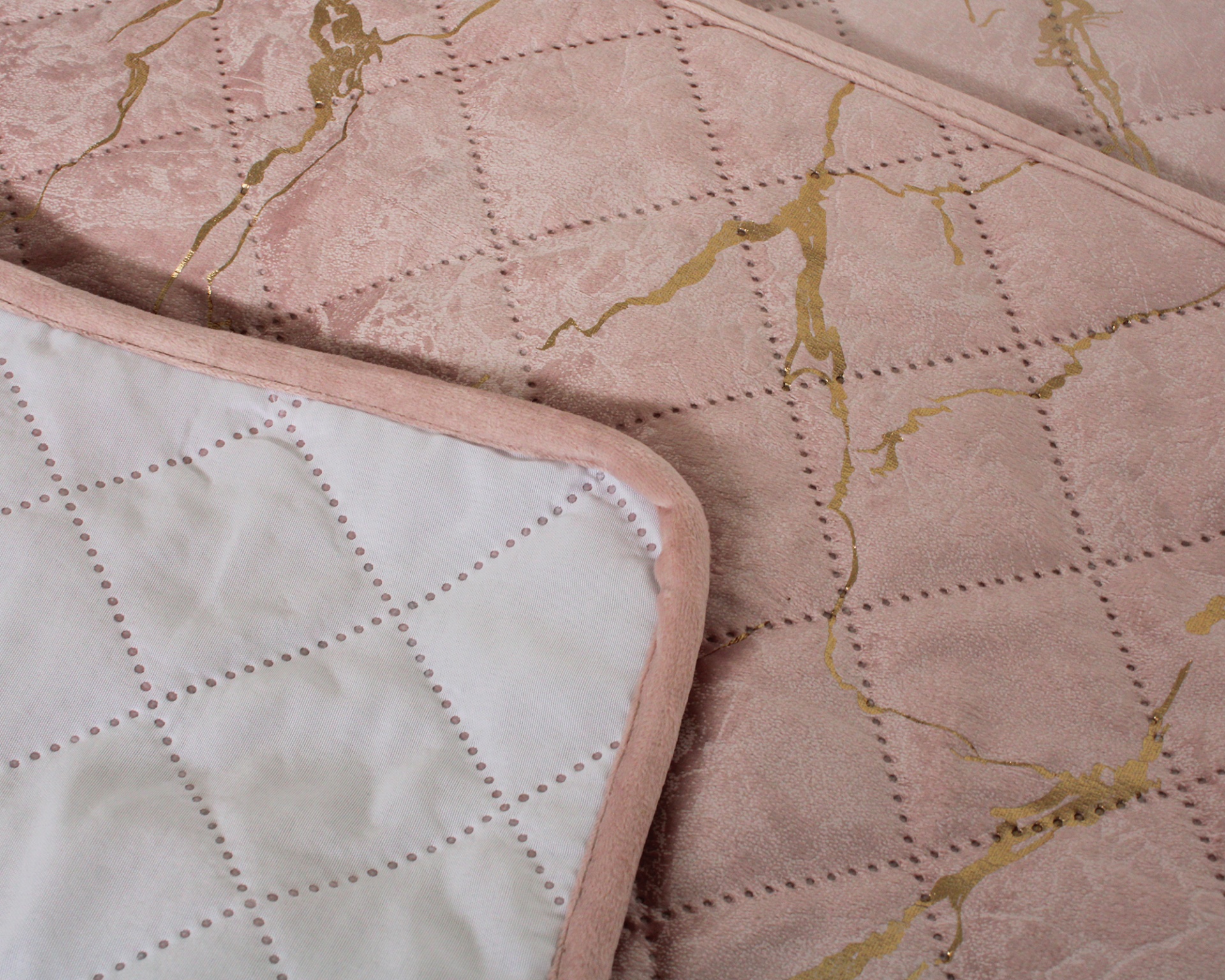 Colcha rosa com padrão quadriculado e detalhes dourados