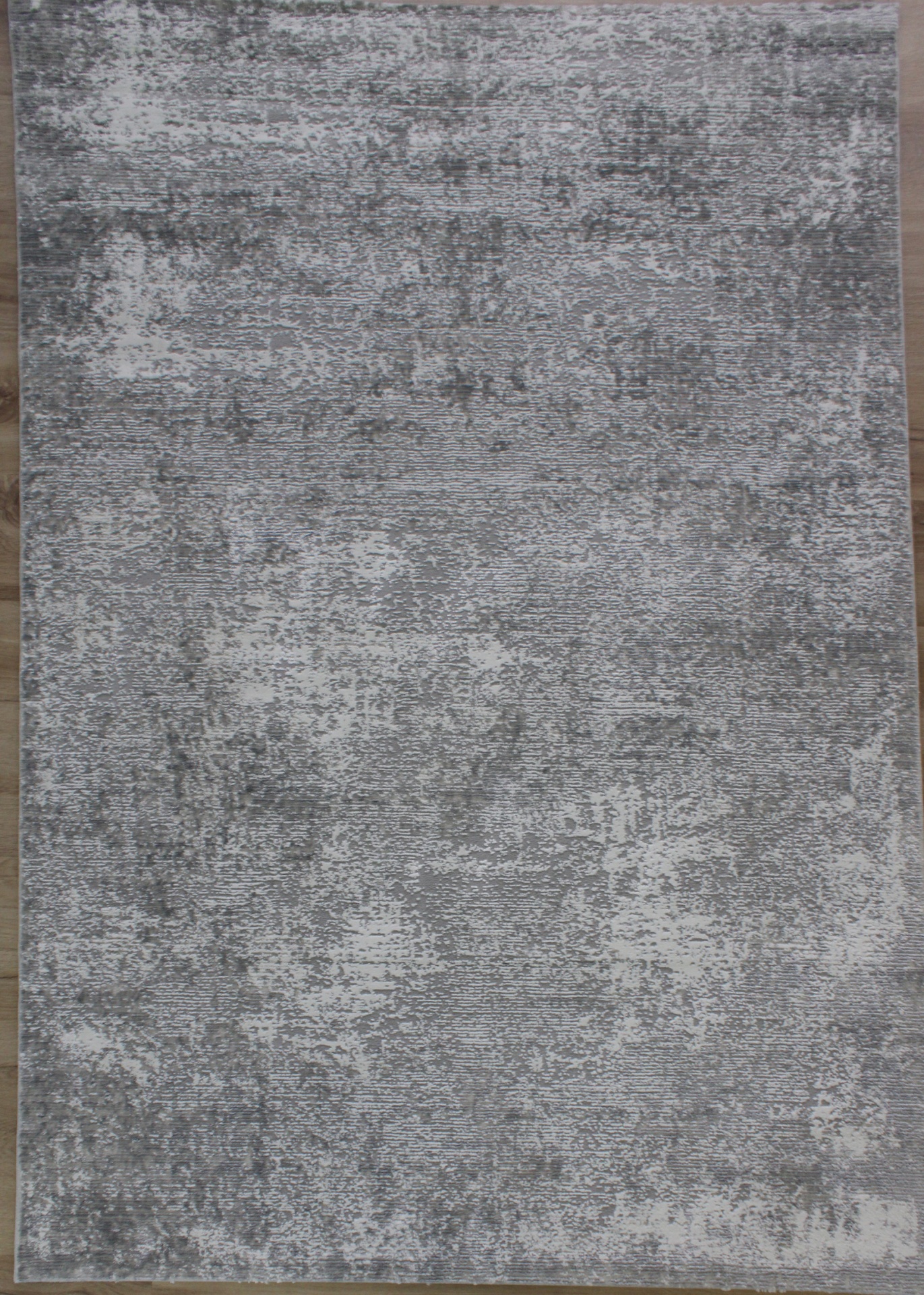 Tapete cinza com padrão abstrato em piso de madeira clara