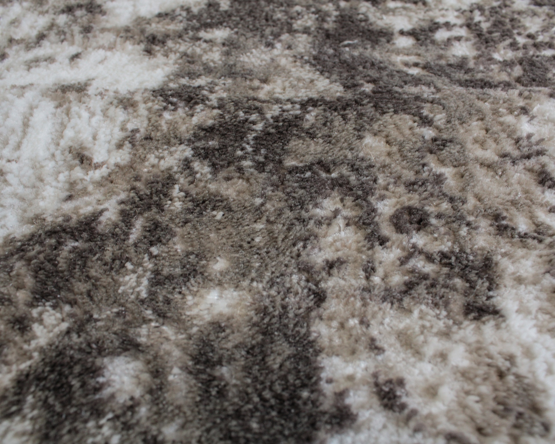 Detalhe de carpete felpudo com padrão abstrato cinza, bege e branco