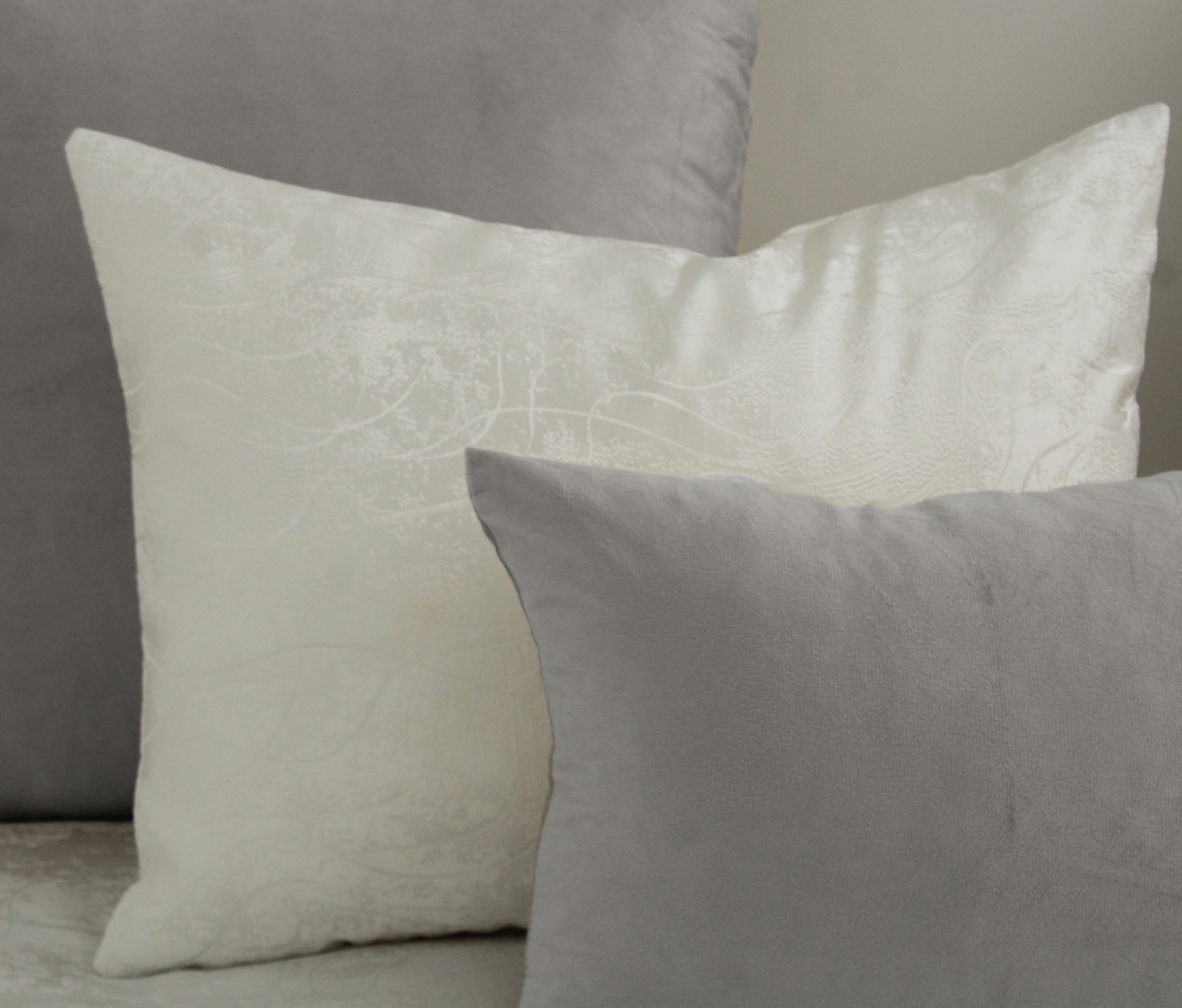 Três almofadas em tons neutros colocadas próximas umas das outras