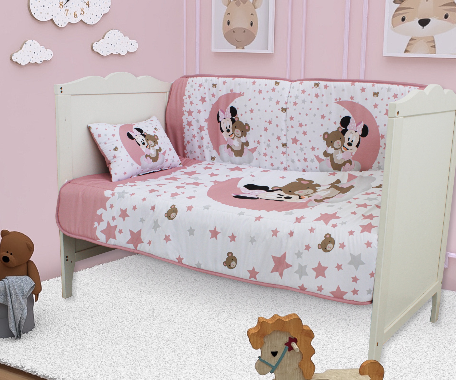 Cama branca infantil com roupa de cama estampada com ursos e estrelas, almofada com padrão igual, paredes cor-de-rosa e quadros de animais.