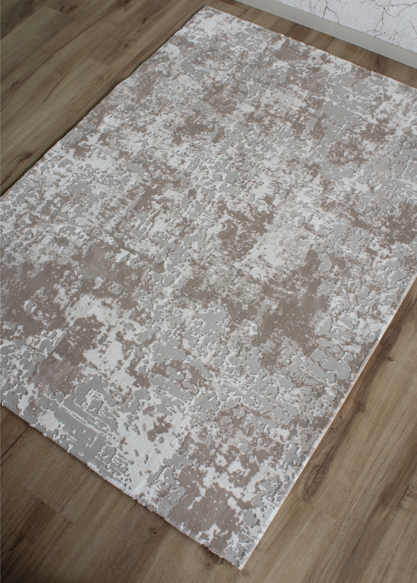 Tapete rectangular bege, cinza e branco sobre chão de madeira clara