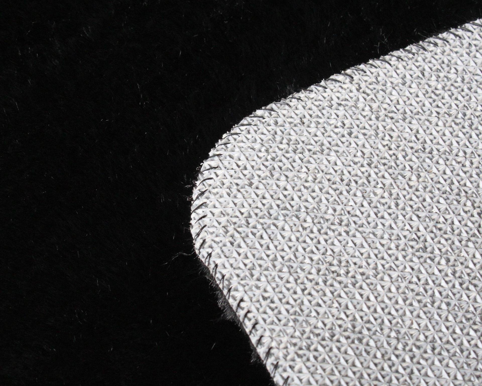 Tapete ou almofada cinza claro texturizada com padrão geométrico sobre fundo preto