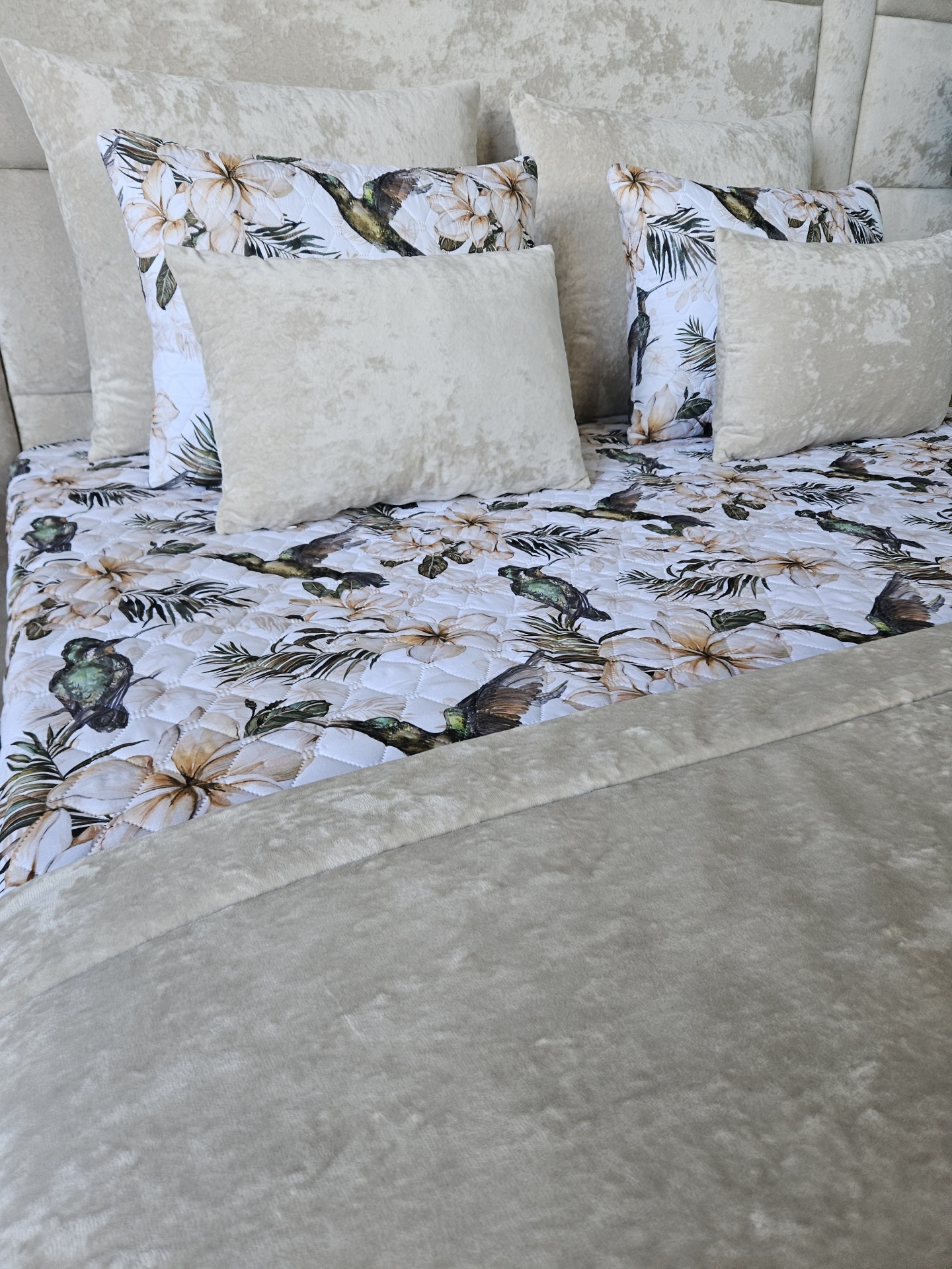 Conjunto de cama com almofadas em tecido cinza e fronhas floridas com pássaros.