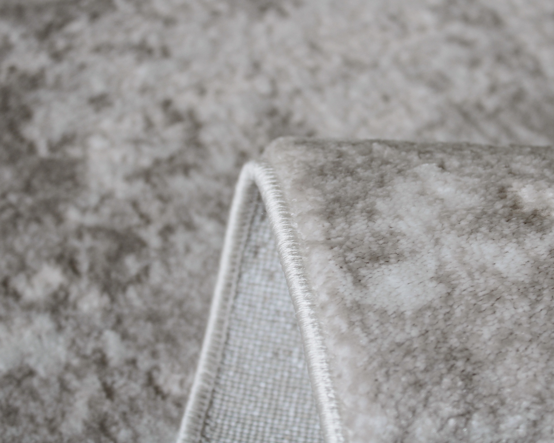Tapete cinzento com padrão abstrato e borda costurada branca dobrado