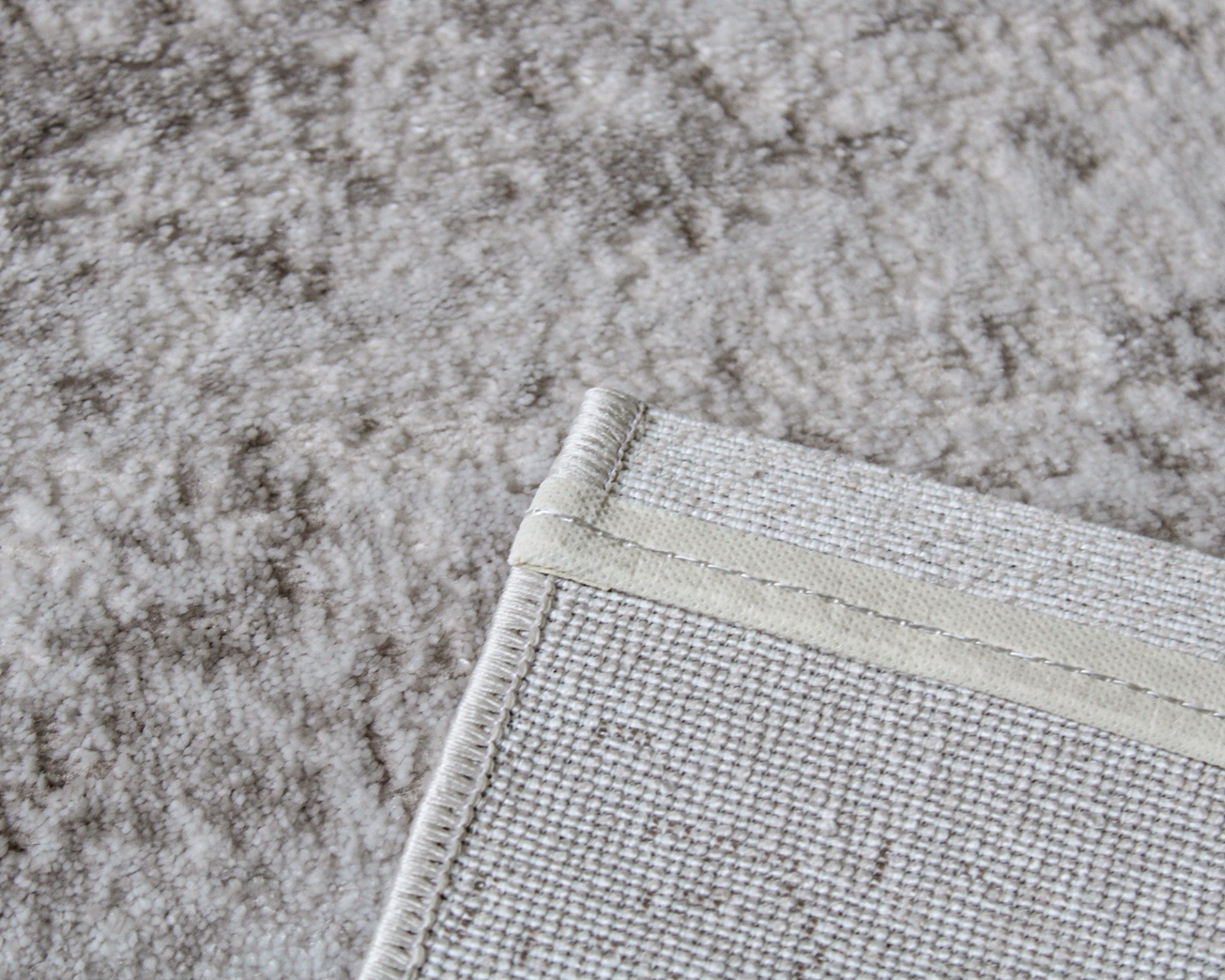 Tapete bege claro com acabamento costurado no verso