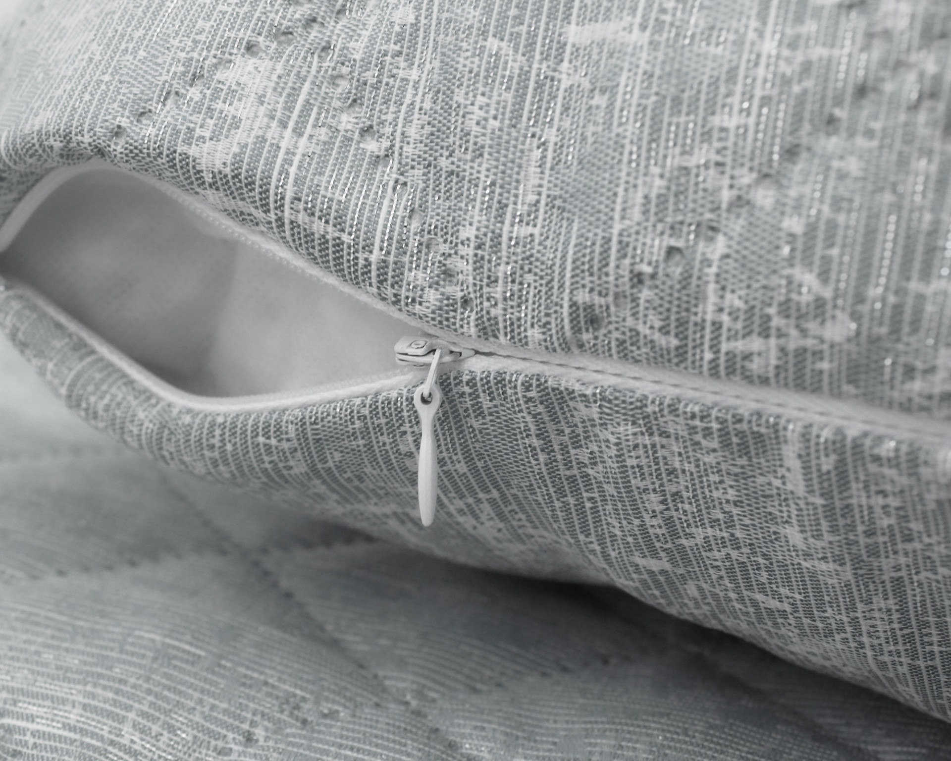 Almofada cinza com padrão geométrico e fecho de correr branco