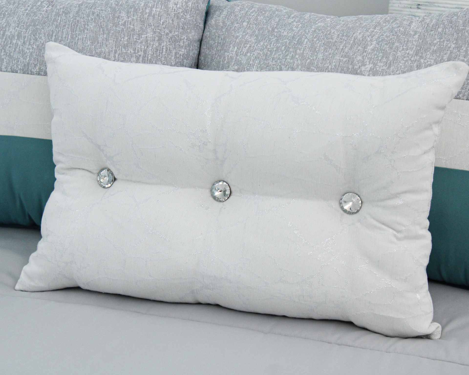 Almofada branca com botões decorativos sobre sofá cinza